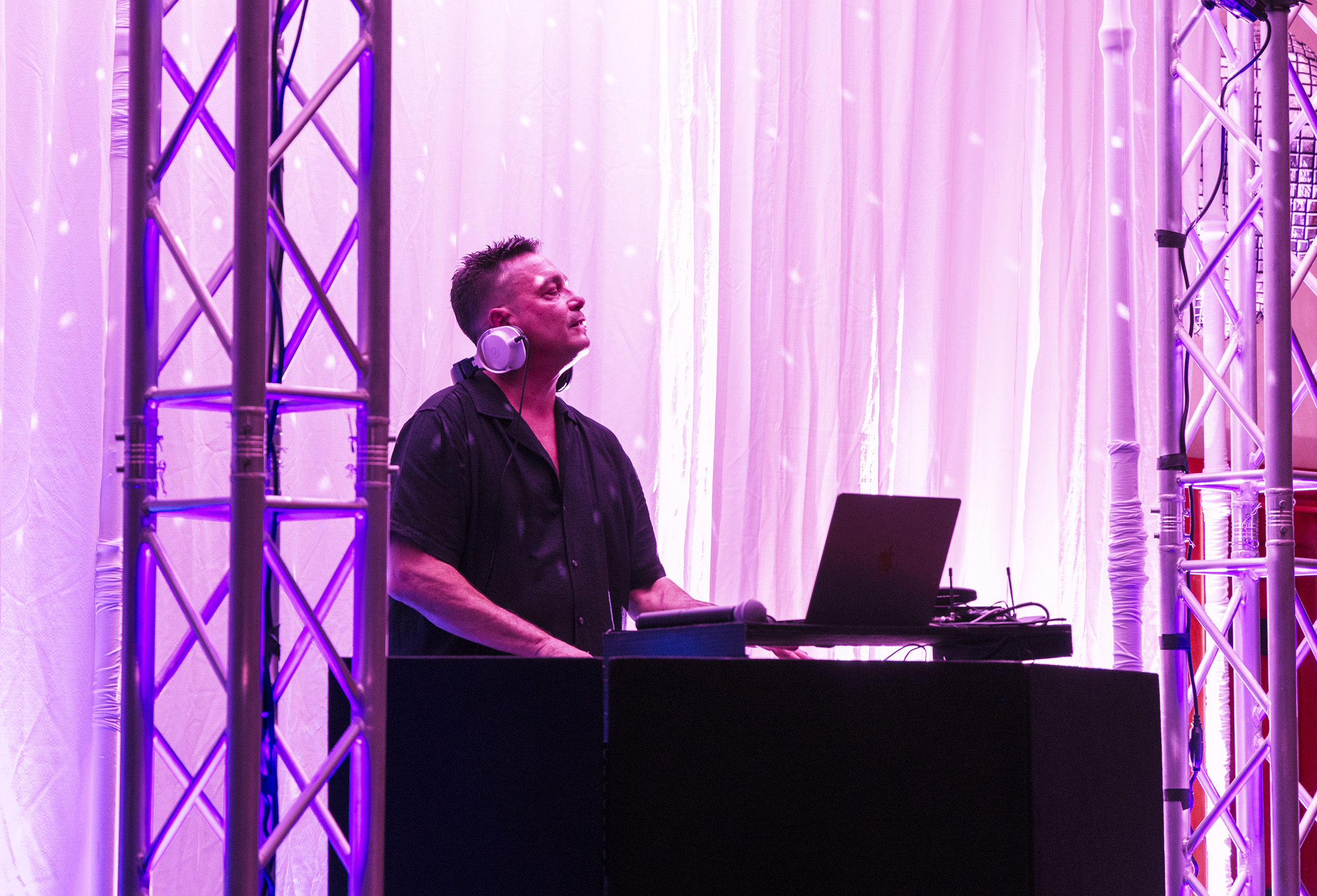 Mr Pink DJing behind his booth with pink event lighting